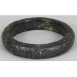 A CHINESE JADE BANGLE, carved to the rounded rim with archaic designs, the predominantly black stone