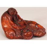A 19TH CENTURY CARVED ROOTWOOD FIGURE OF A RECLINING SAGE, the sage stroking his beard, 7.3in long &