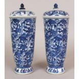 A PAIR OF CHINESE BLUE & WHITE PORCELAIN URNS & COVERS, each decorated with panels of stylised
