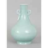 A CHINESE CELADON PORCELAIN VASE, the neck moulded with double key-fret handles, the base with a