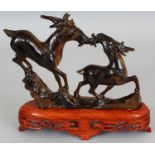 A CHINESE TIGER'S EYE HARDSTONE CARVING OF TWO DEER, together with a fixed wood stand, 7.1in