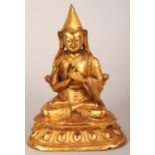 A TIBETAN GILT BRONZE FIGURE OF A LAMA, the priest seated in dhyanasana on a double lotus plinth,