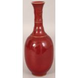 A CHINESE SANG-DE-BOEUF PORCELAIN BOTTLE VASE, with ribbed neck, the sides applied with a mottled