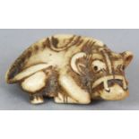 A JAPANESE MEIJI PERIOD STAGHORN NETSUKE OF A RECUMBENT OXEN, one of its eyes inlaid, 1.9in long.
