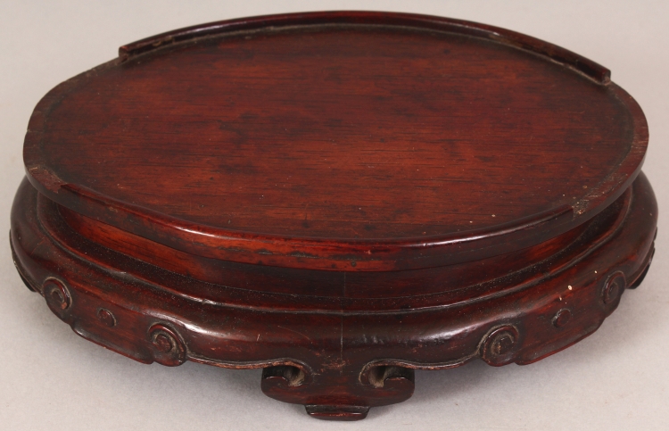 A 19TH CENTURY CHINESE OVAL CARVED HARDWOOD STAND, with ruyi form feet and ruyi carved frieze, 7.8in