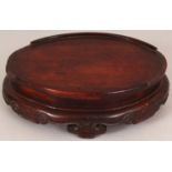 A 19TH CENTURY CHINESE OVAL CARVED HARDWOOD STAND, with ruyi form feet and ruyi carved frieze, 7.8in