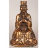 A CHINESE GILT BRONZE FIGURE OF A SEATED OFFICIAL, bearing a tablet, the reverse with incised
