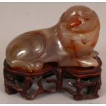 A 19TH/20TH CENTURY CHINESE AGATE CARVING OF A RECUMBENT BUDDHISTIC LION, together with a fitted