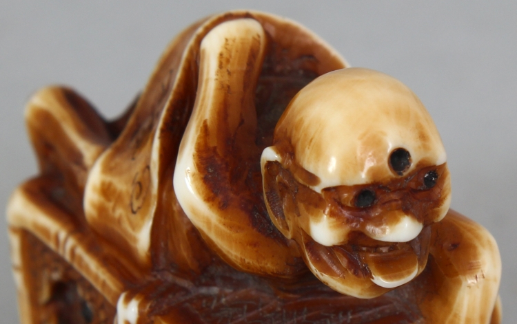 A SIGNED JAPANESE MEIJI PERIOD STAINED IVORY NETSUKE OF A DEMON, lying astride a rectangular reed - Image 5 of 9