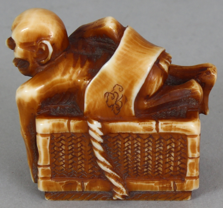 A SIGNED JAPANESE MEIJI PERIOD STAINED IVORY NETSUKE OF A DEMON, lying astride a rectangular reed - Image 3 of 9