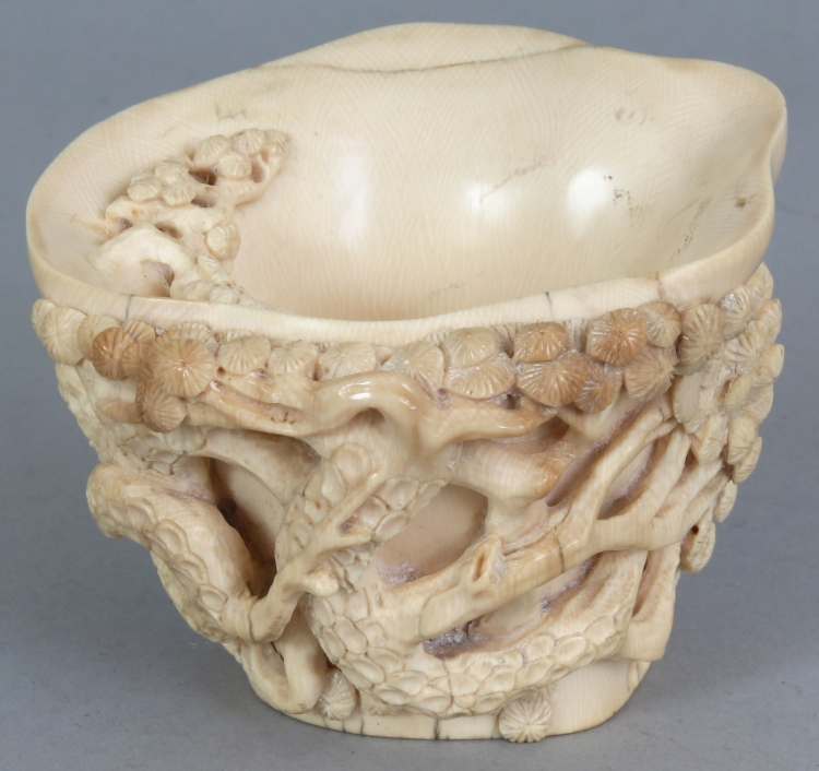 A GOOD QUALITY 19TH CENTURY CHINESE IVORY LIBATION CUP, the sides carved in high relief with