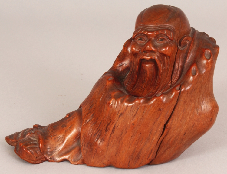 A GOOD QUALITY 19TH CARVED ROOTWOOD FIGURE OF A RECLINING SAGE, wrapped in a well grained cloak, 6.