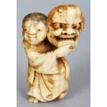 A JAPANESE MEIJI PERIOD IVORY NETSUKE OF A STANDING BOY, unsigned, the boy bearing aloft a Noh mask,