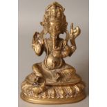 A NEPALESE OR NORTH INDIAN GILT BRONZE FIGURE OF GANESHA, seated on a lotus plinth, 6.8in high.
