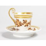 A FURSTENBERG CUP AND SAUCER with gilt handle and bands of fruiting vines. Mark in blue.