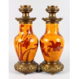 AN UNUSUAL PAIR OF SEVRES ORANGE VASES painted with flowers, with metal mounts, converted to