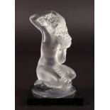 A SMALL LALIQUE SEATED NUDE on a rock with black square base. Etched Lalique, France. 3.5ins high.