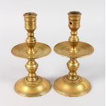 A PAIR OF EARLY DUTCH BRASS CANDLESTICKS with drip pan. 8.5ins high.