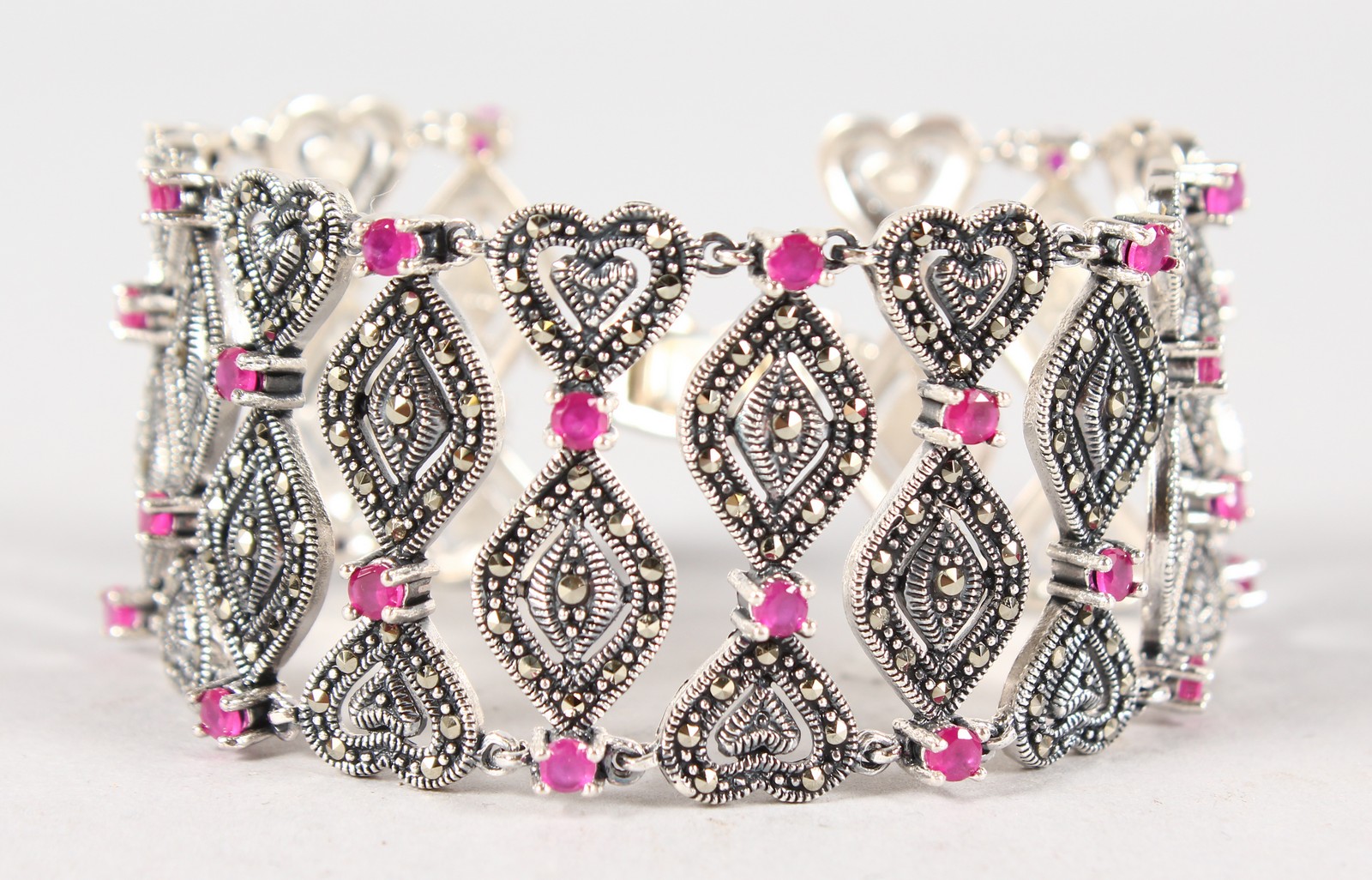 A SILVER, MARCASITE AND RUBY WIDE BRACELET.