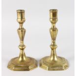 A PAIR OF EARLY BRASS CANDLESTICKS with square bases with cut off corners. 7ins high.