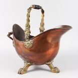 A GOOD COPPER AND BRASS HELMET SHAPED COAL SCUTTLE on three iron claw feet.