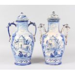 A LARGE PAIR OF DELFT BLUE AND WHITE TWO-HANDLED POTTERY VASES AND COVERS painted with a town scene.