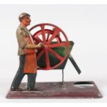 AN EARLY TIN PLATE TOY, a man turning the wheel. 6ins long.