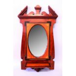 AN EDWARDIAN MAHOGANY FRAMED OVAL MIRROR with bevelled edge, broken arched pediment and small shelf.