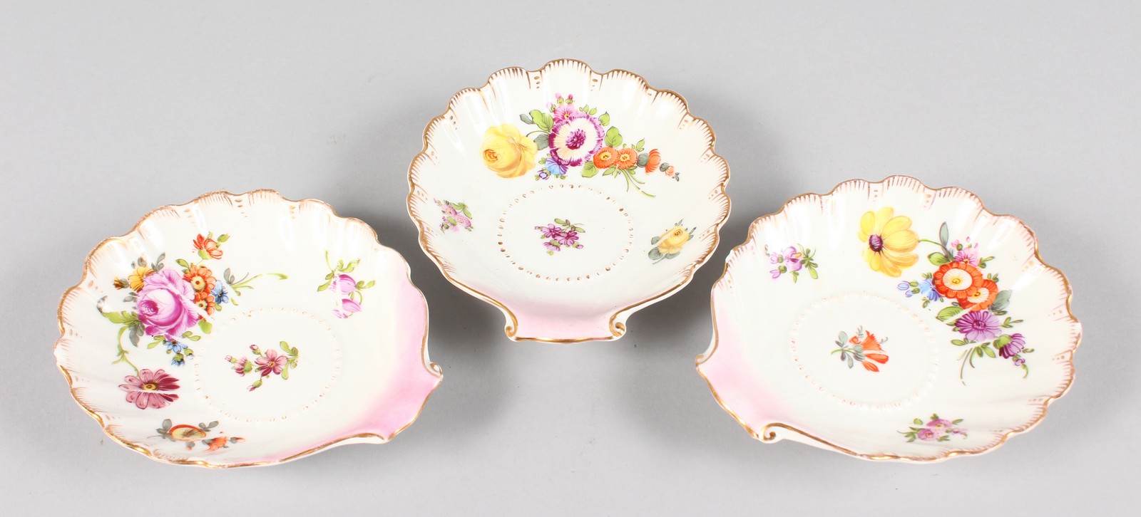 THREE SMALL DRESDEN SHELL DISHES painted with flowers. 5ins.