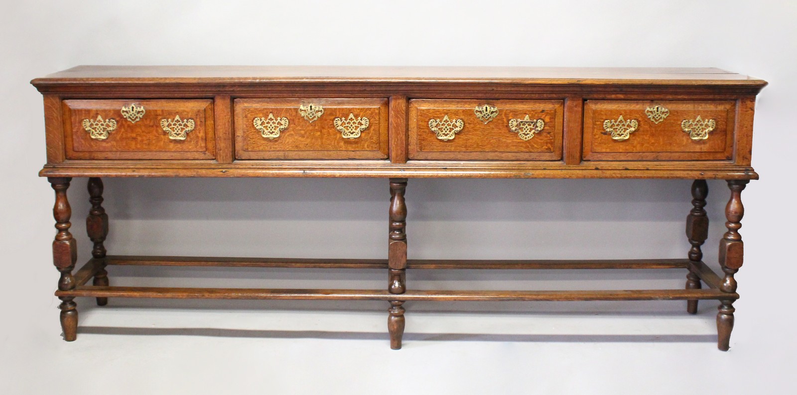 A GOOD 18TH CENTURY OAK DRESSER BASE with plain top, four deep drawers with pierced brass handles