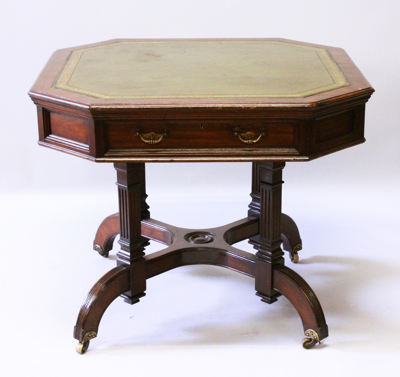 A MAPLE & CO AESTHETIC MAHOGANY OCTAGONAL DRUM TABLE with green leather top, two frieze drawers,