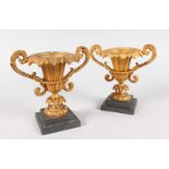 A PAIR OF 19TH CENTURY FRENCH TWO-HANDLED URN SHAPED VASES on stepped marble bases. 6.5ins high.