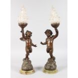 A PAIR OF BRONZED CUPID CANDLESTICKS converted to electricity.