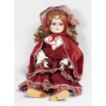 A GOOD GERMAN BISQUE HEADED DOLL wearing a velvet cloak.