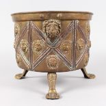 A BRASS CIRCULAR JARDINIERE, with lion ring handles, on claw feet. 9ins high.