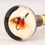 A SUPERB FISHING THEMED WALKING CANE, the Perspex handle inset with a fishing fly. 39ins long.