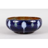 A ROYAL DOULTON STONEWARE CIRCULAR FRUIT BOWL, blue body with lilac leaves. 8.5ins diameter.