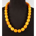 A STRING OF YELLOW AMBER BEADS, each bead 2.5cms, 80cms long.