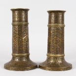 A RARE PAIR OF 17TH CENTURY ISLAMIC ETCHED AND PIERCED TORCH STANDS of circular form, etched with