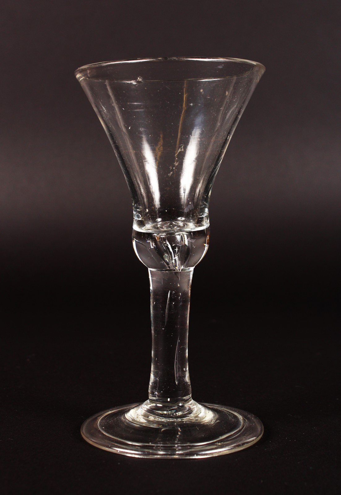AN INVERTED BELL SHAPED BOWL WINE GLASS with plain stem. 5.5ins high.