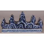 A CHINESE MING STYLE BLUE & WHITE PORCELAIN BRUSH REST, moulded in the form of mountain peaks