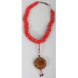 A CHINESE CORAL STYLE BEADED NECKLACE, with a dependant brown jade-like hardstone disc pendant,