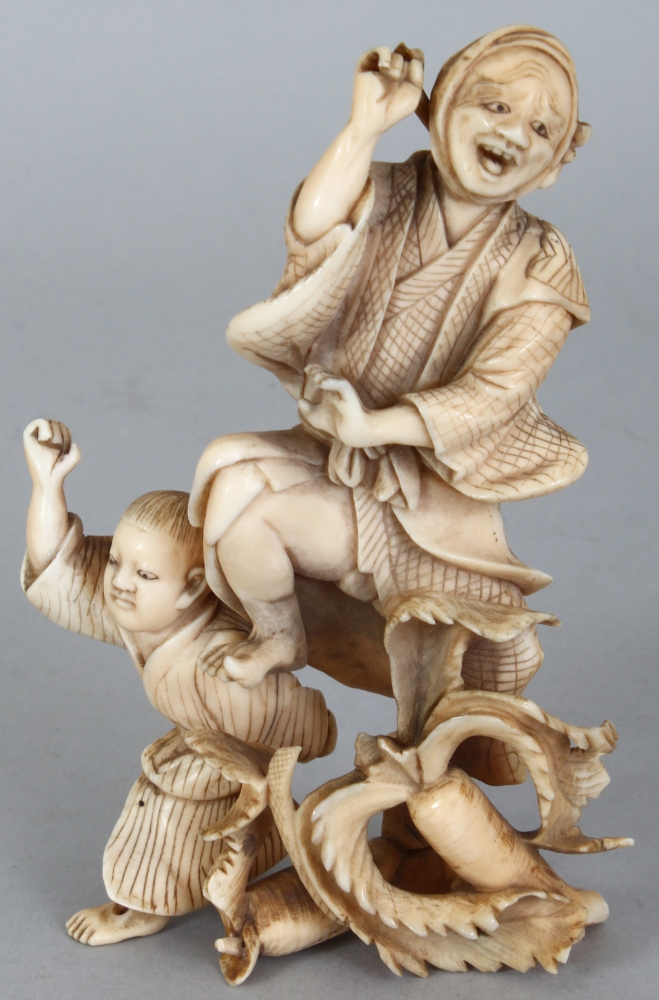 A JAPANESE MEIJI PERIOD IVORY OKIMONO OF A FARMER & HIS SON, unsigned, leaping before two giant