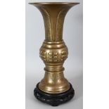 AN EARLY 20TH CENTURY CHINESE POLISHED BRONZE GU VASE, together with a carved wood stand, the centre