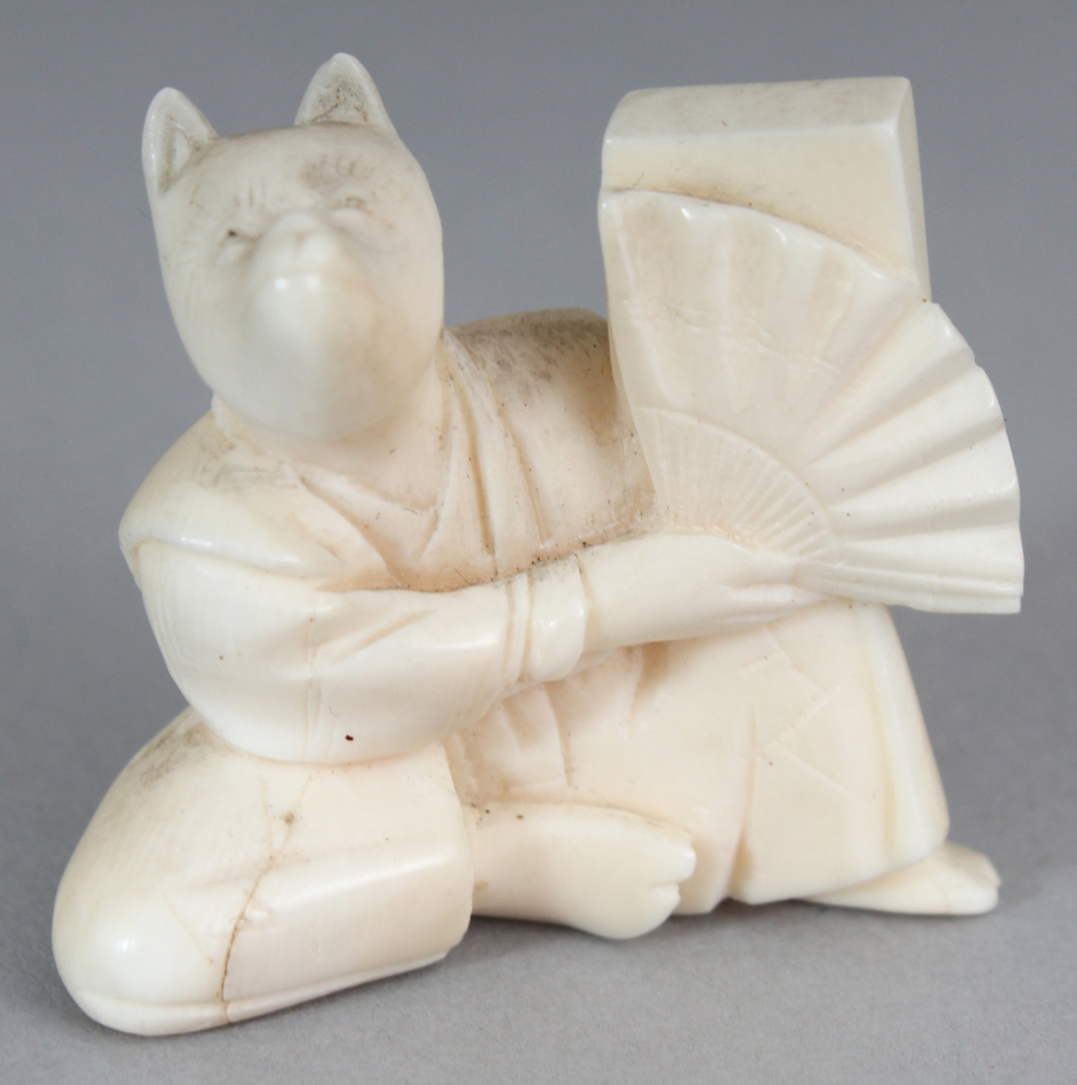 AN EARLY 20TH CENTURY JAPANESE IVORY NETSUKE OF A SEATED FOX, unsigned, the fox holding a fan, 1.