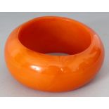 A LARGE AMBER-STYLE BANGLE, 3.8in diameter, the inner rim 2.7in diameter.