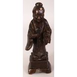 A 17TH CENTURY CHINESE BRONZE FIGURE OF A SAGE, standing on a square-section plinth and unusually