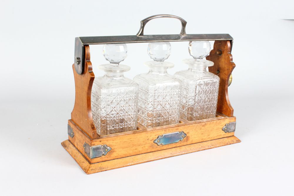 A THREE DECANTER OAK FRAMED TANTALUS with plated handle and mounts. 15ins long. - Image 2 of 2