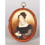 A VICTORIAN OVAL PORTRAIT MINIATURE OF A LADY holding a letter. 8cms x 6.5cms in a leather case.