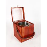 A SMALL SQUARE LEATHER TRAVELLING ICE BOX with metal liner and carrying handle. 8ins high.